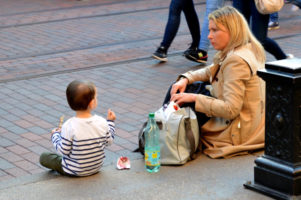 Mother and child sitting on the pavement