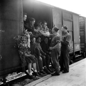 Militairen nemen afscheid van een aantal mannen in een goederenwagon. De deurop, Bestanddeelnr 900-5062