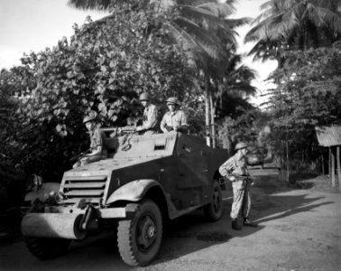 Militairen met wapens in de aanslag zitten op of staan bij een pantserwagen (M3 , Bestanddeelnr 10545