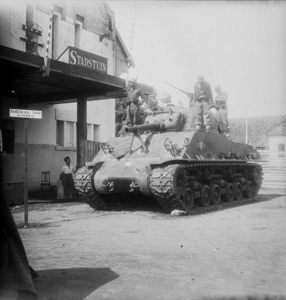 Militairen op een Sherman tank voor een gebouw met het bord 'Stadstuin'. Op het…, Bestanddeelnr 10956