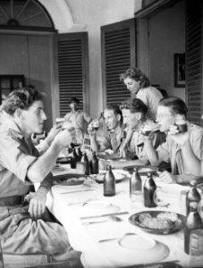 Militairen aan de maaltijd drinken bier, worden bediend door een vrouw, Bestanddeelnr 13181
