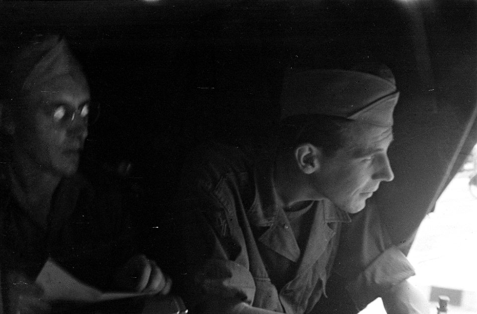 Militairen (oorlogsverslaggevers) in een vliegtuig kijken naar buiten, Bestanddeelnr 6110