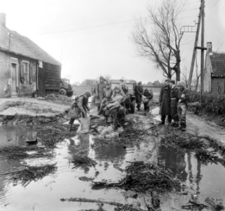 Militairen bezig met het dempen van een gat met zandzakken, Bestanddeelnr 905-5146