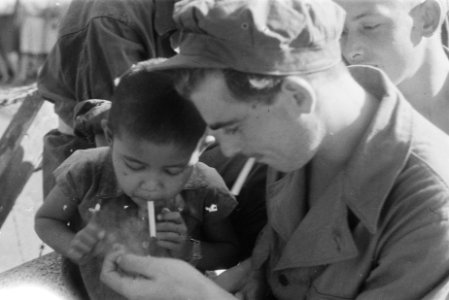 Militairen geven een Indonesisch jongetje met een sigaret een vuurtje, Bestanddeelnr 135-3-5