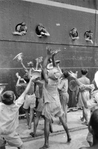 Militairen gooien uit de patrijspoort sigaretten voor de kinderen op de kade, Bestanddeelnr 92-2-4