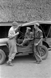 Militairen met glazen in de handen poseren voor een jeep, Bestanddeelnr 86-4-6