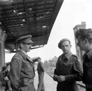 Militairen in gesprek op een spoorwegstation. Links een kapitein van de Lancash, Bestanddeelnr 900-5058