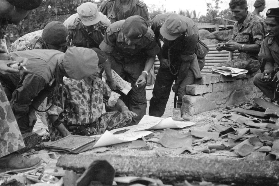Militairen bestuderen kaarten op de vloer van een verwoest gebouw, Bestanddeelnr 333-3-4