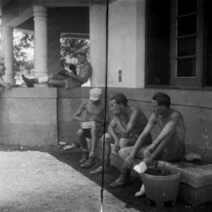 Militairen in shorts zitten in de schaduw van een gebouw, Bestanddeelnr 8275
