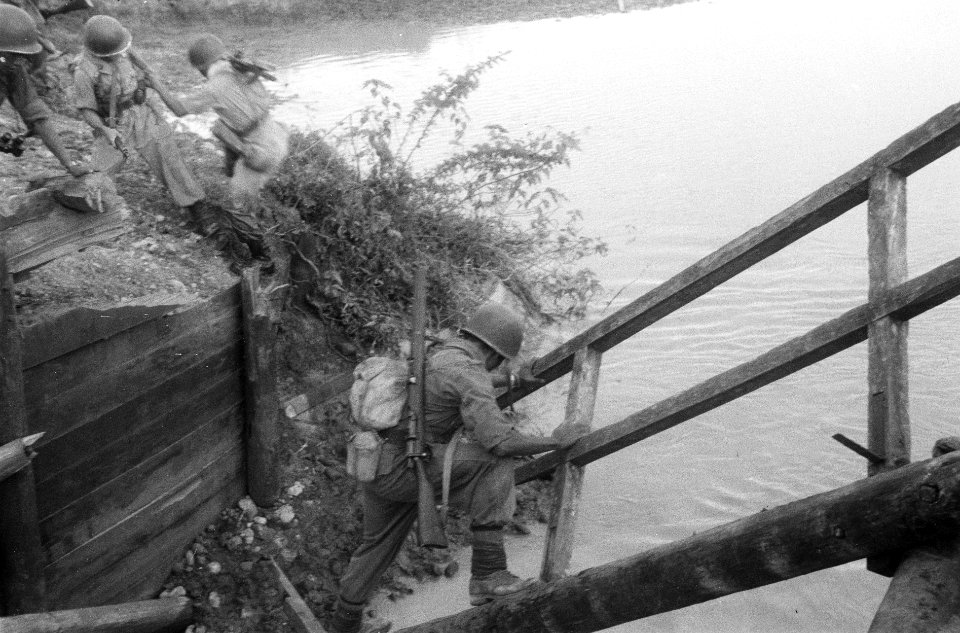 Militairen klimmen over een hek van een vernielde brug naar de andere kant van , Bestanddeelnr 270