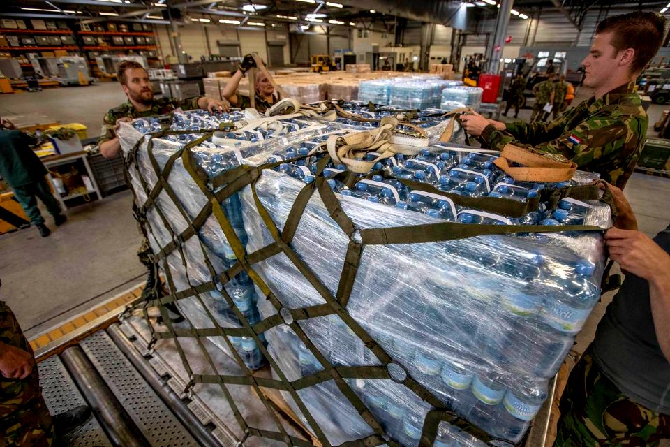 Militairen zetten op Vliegbasis Eindhoven water en voedsel klaar voor transport