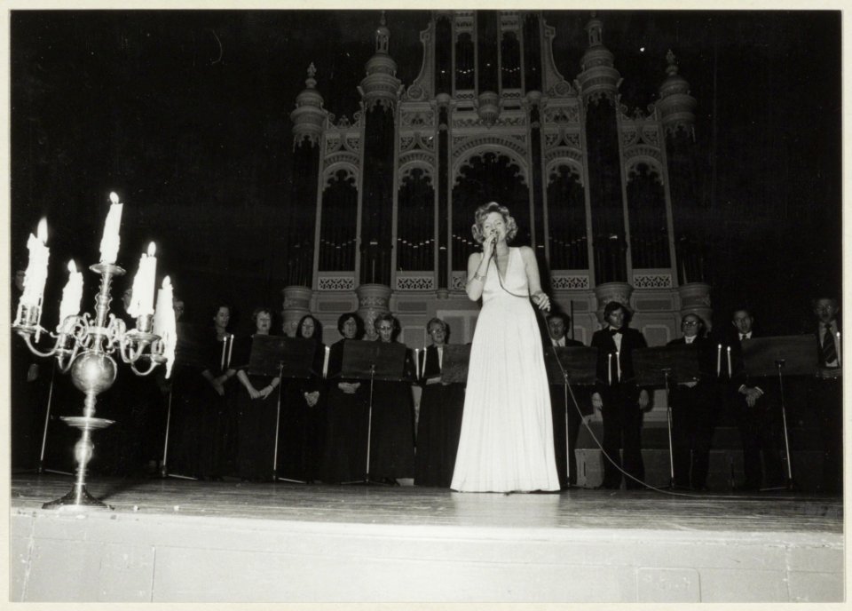 Mieke Telkamp zingt het slotlied op een kerstgala in het Concertgebouw, waarbij het Haarlems Kamerkoor haar begeleid. NL-HlmNHA 54005108