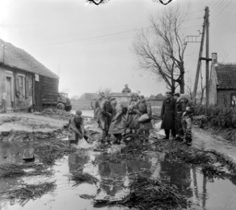 Militairen bezig met het dempen van een gat met zandzakken, Bestanddeelnr 905-5145