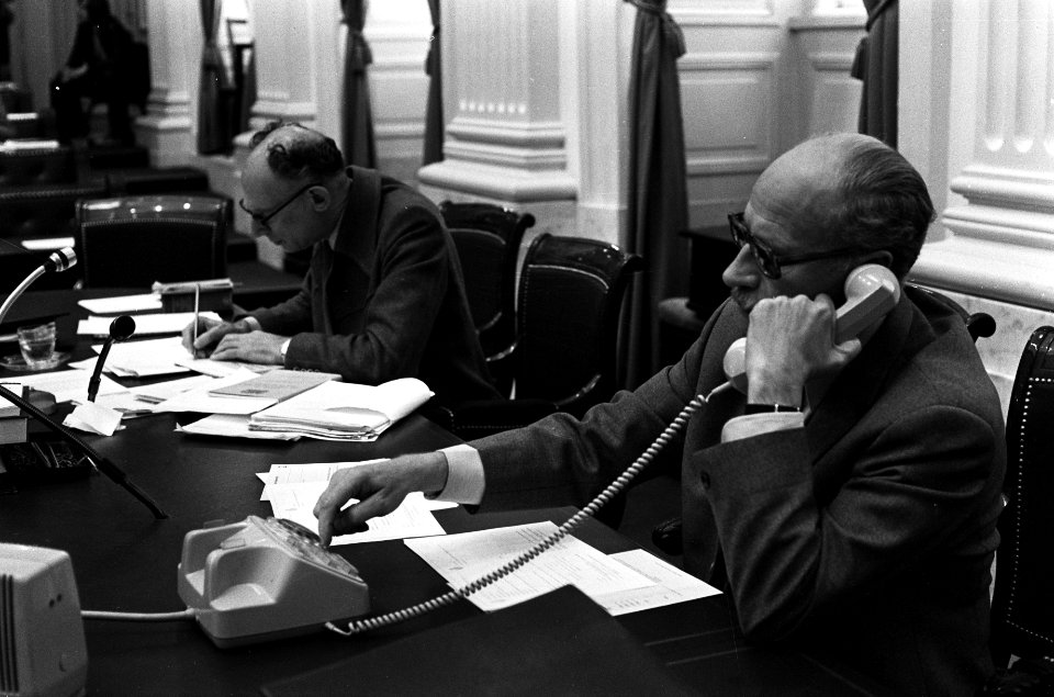 Minister Van Doorn aan de telefoon, achter hem Voogd (PvdA), de indiener van het, Bestanddeelnr 927-9689