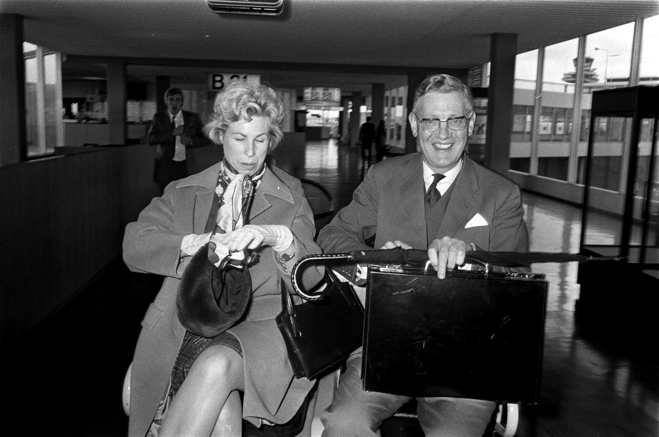 Minister Udink van Ontwikkelingshulp arriveert op Schiphol en echtgenote, Bestanddeelnr 922-9844