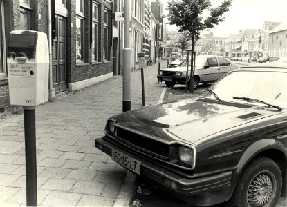 Nassaulaan, ziende naar het zuiden, zwart gespoten parkeermeters. Geschonken in 1986 door United Photos de Boer bv. - Gepubliceerd in het Haarlems Dagblad van 16-07-1983. Identificatienummer 54-016763