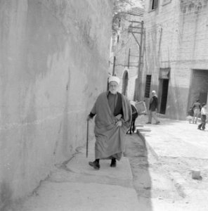 Nazareth Man in lang gewaad, met hoofddeksel en wandelstok in een smalle straat, Bestanddeelnr 255-3275