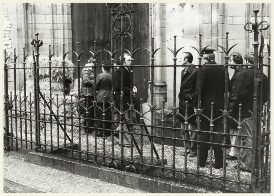 Na het ontploffen van een nep-bom worden de strobalen bij de kerk opgeruimd. NL-HlmNHA 54005121