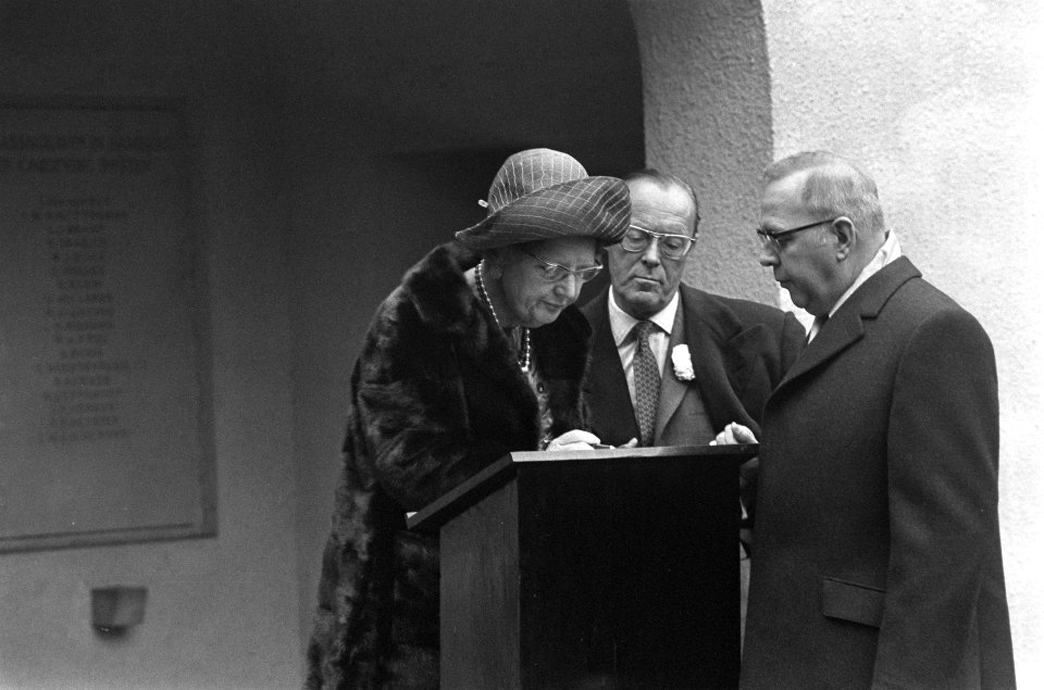 Na de kranslegging tekent koningin Juliana het gastenboek van de begraafplaats, Bestanddeelnr 925-0877