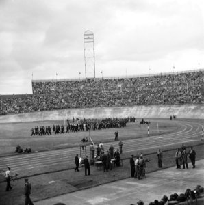 Muziekband paradeert over het veld van het Olympisch Stadion. Aan de zijkant is, Bestanddeelnr 900-4592