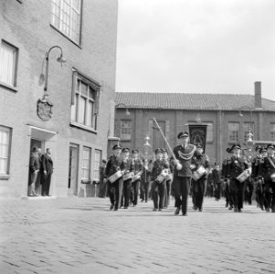 Muziekkorps passeert mannen in deuropening, links fabrieksdirecteur Jan van Abbe, Bestanddeelnr 255-8436