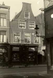 Nolf's Goedkoope Apotheek, ziende vanuit de Nieuwe Kruisstraat, naar het westen. Nolf's apotheek Kruisstraat 26 voor de verbouwing, met toegangspoort tot de Graaf Meinderssteeg. Geschonken i, NL-HlmNHA 54005625