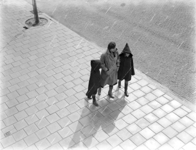 Nell Langlais loopt met haar dochters Renée (links) en Hans in de regen over str, Bestanddeelnr 252-0480 photo