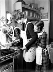 Nell Langlais keert een pannenkoek om terwijl Hans (rechts) en Renée toekijken, Bestanddeelnr 189-1062 photo