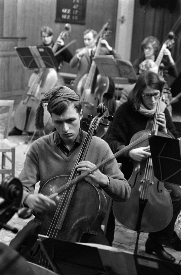 Nederlands Studenten Orkest repeteert in Ruine kerk te Bergen. Cellist met petje, Bestanddeelnr 923-1260