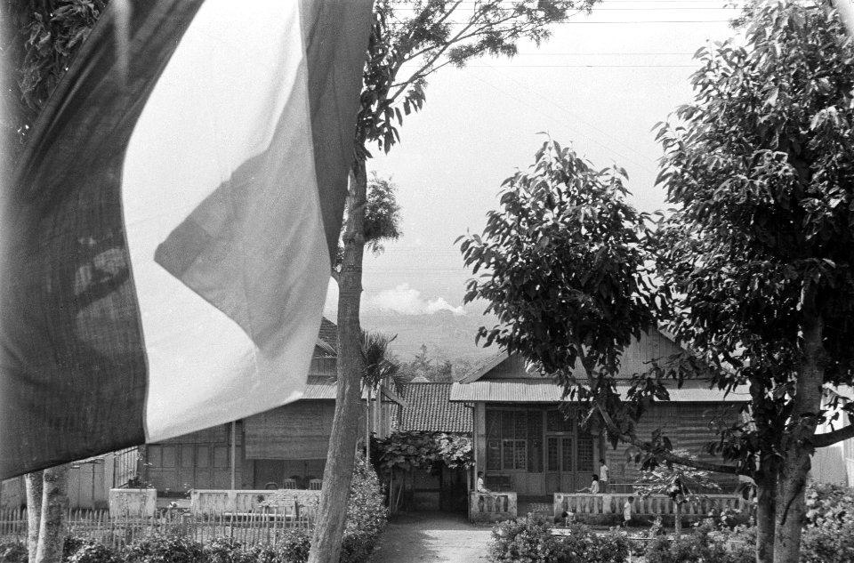 Nederlandse vlag wappert in nederzetting met huizen, Bestanddeelnr 4474
