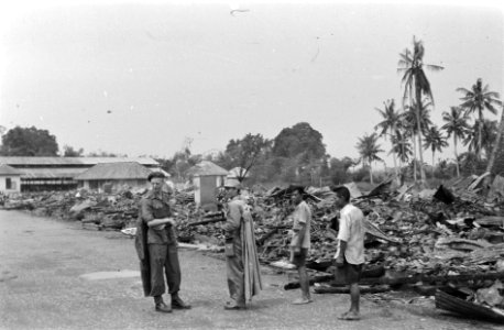 Nederlandse militair staat tussen de verwoestingen. Naast hem een Japanse krijgs, Bestanddeelnr 7483