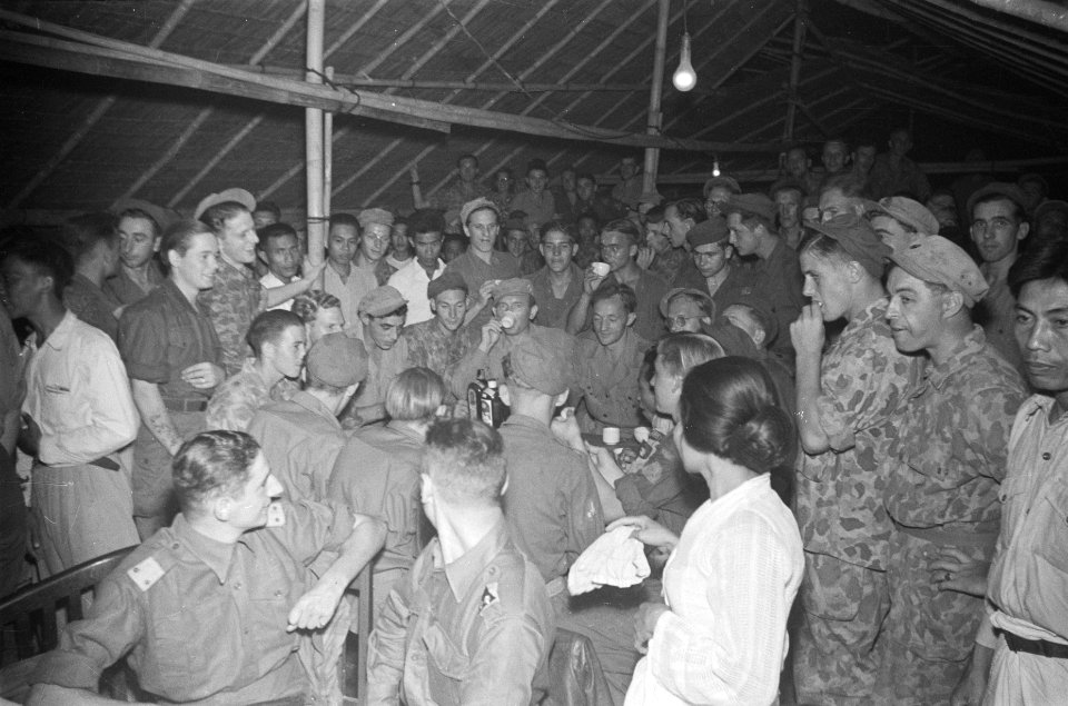 Nederlandse militairen in een barak Een groep mannen zit om een tafel met fless, Bestanddeelnr 85B-6-2