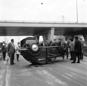 Omstanders bekijken de op zijn kop liggende Volkswagen Kever, Bestanddeelnr 919-6025