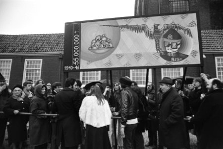 Omstanders bij de herdenking met een spandoek, Bestanddeelnr 929-0468