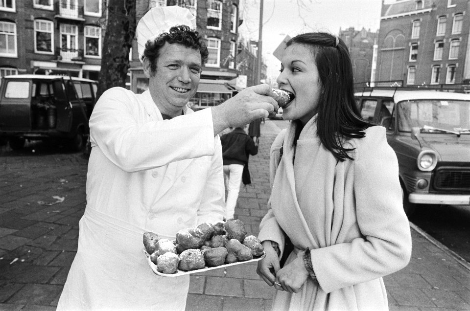 Oliebollenverkoop in Amsterdam gestart meisje eet oliebol van bakker, Bestanddeelnr 930-0589