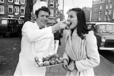 Oliebollenverkoop in Amsterdam gestart meisje eet oliebol van bakker, Bestanddeelnr 930-0589