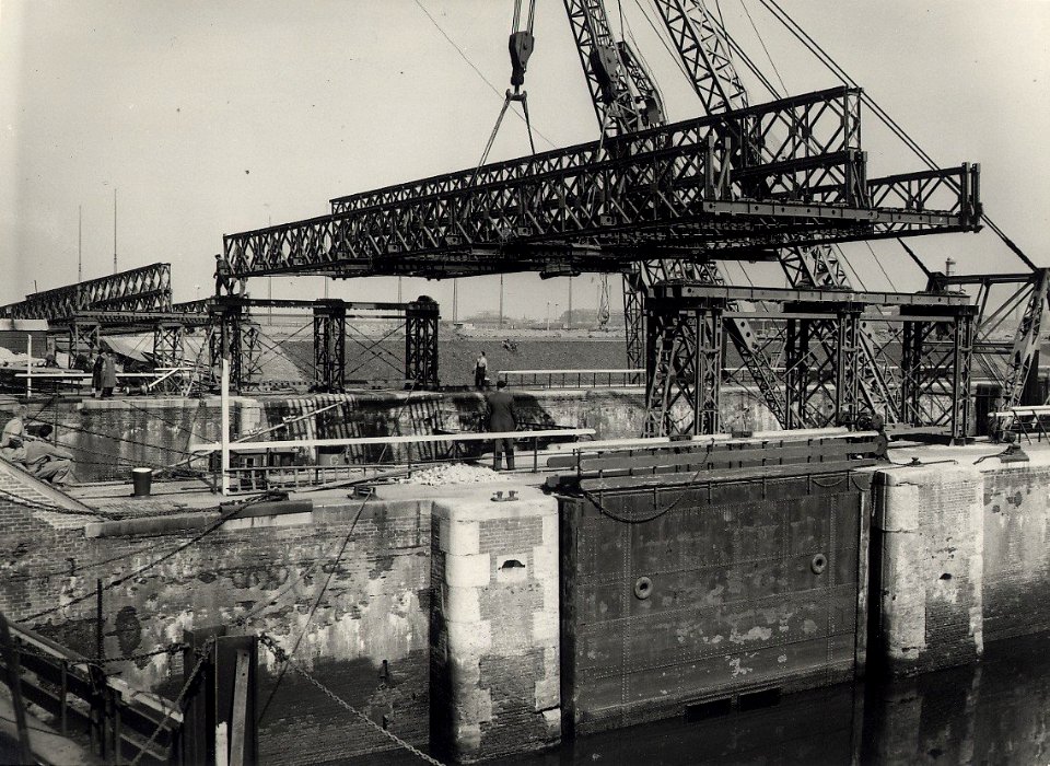 Om het verkeer bij de Velserponten te ontlasten, wordt over de sluizen van IJmuiden een Baileybrug gebouwd. Het werk vorderd snel, de grote overspanning van de Zuidersluis wordt op haar plaa, NL-HlmNHA 54010752