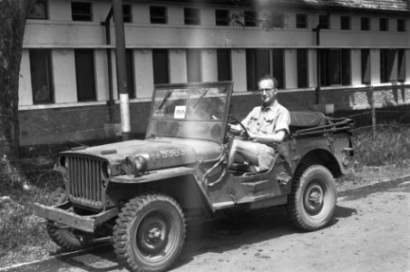 Oorlogsverslagger poseert, zittend achter het stuur van een jeep (op de voorruit, Bestanddeelnr 5906