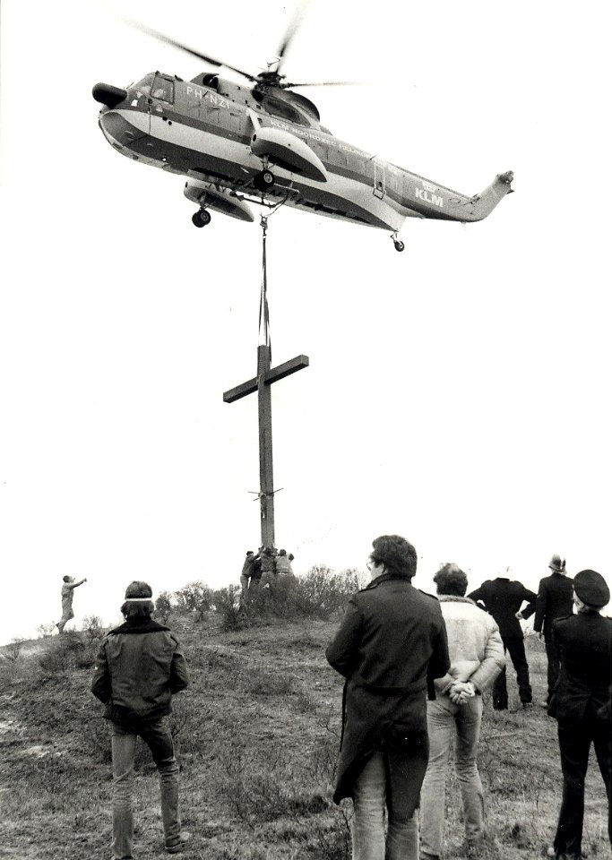 Op de Erebegraafplaats wordt met behulp van een helicopter een nieuw houten kruis geplaatst aangezien de vorige, geplaatst in 1945, op 4 december 1976 door blikseminslag totaal werd vernield, NL-HlmNHA 1478 25900 K 38