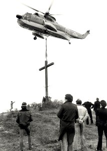 Op de Erebegraafplaats wordt met behulp van een helicopter een nieuw houten kruis geplaatst aangezien de vorige, geplaatst in 1945, op 4 december 1976 door blikseminslag totaal werd vernield, NL-HlmNHA 1478 25900 K 38