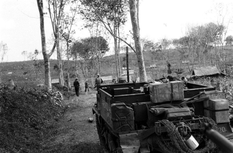 Op een weg omzoomd met bomen staat een bren-carrier. Daarvoor lopen Nederlandse , Bestanddeelnr 5701