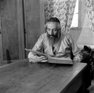 Oost-Europese rabbijn en schriftgeleerde in de wijk Mea Shearim, aan tafel zitte, Bestanddeelnr 255-0411