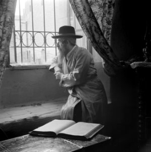 Oost-Europese rabbijn en schriftgeleerde in de wijk Mea Shearim, zittend bij een, Bestanddeelnr 255-0412
