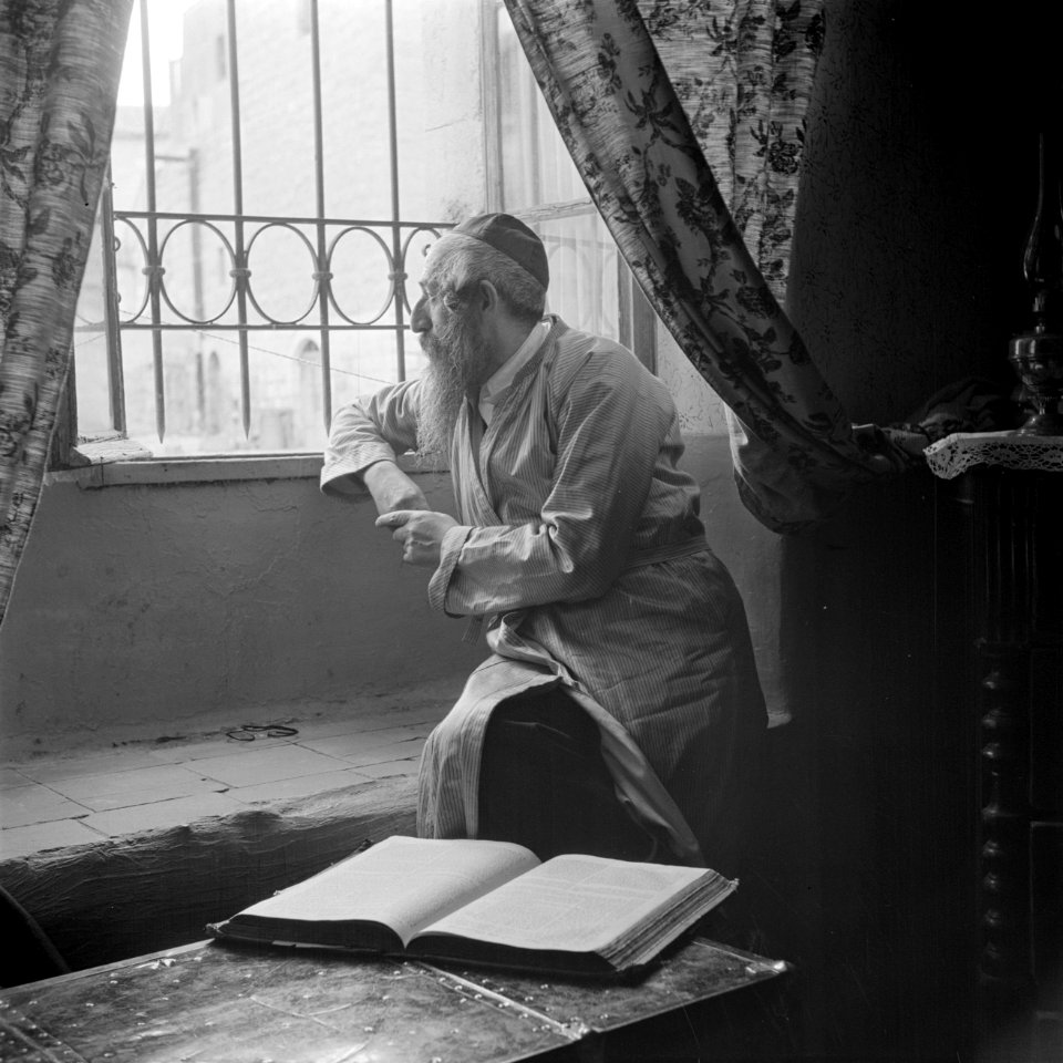 Oost-Europese rabbijn en schriftgeleerde in de wijk Mea Shearim, zittend bij een, Bestanddeelnr 255-0413