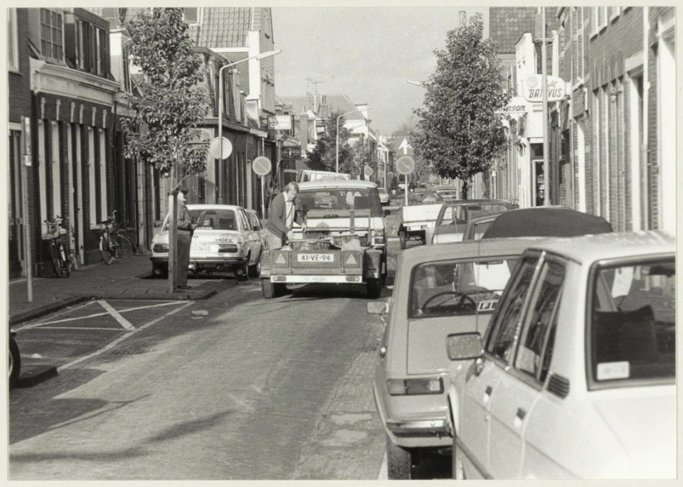 Ondernemer Mul en geparkeerde auto's in de Oranjeboomstraat ziende naar het noorden. NL-HlmNHA 54010158