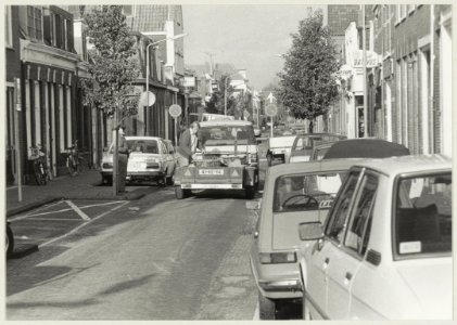 Ondernemer Mul en geparkeerde auto's in de Oranjeboomstraat ziende naar het noorden. NL-HlmNHA 54010158