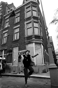 Ontruiming kraakpand Houthorststraat in Amsterdam (eigendom USSR), blije kraakster verlaat het pand, op achtergrond pand en (l) ME, Bestanddeelnr 931-4147