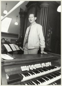 Organist Niek van der Aar bij het kerkorgel van de Sint-Jacobus de Meerderekerk aan de Liedeweg in Haarlemmerliede. NL-HlmNHA 54013078