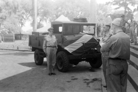 Officier lijkt een toespraak te houden. Naast hem de vrachtwagen met Nederlands, Bestanddeelnr 54-2-5