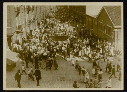Optocht van kinderen en volwassenen met harmonieorkest achter een spandoek met o, Bestanddeelnr 158-1254